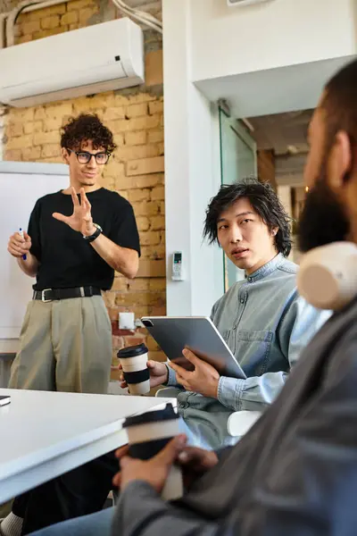 Two colleagues listen attentively as a team leader discusses strategies during a creative meeting. — Stock Photo