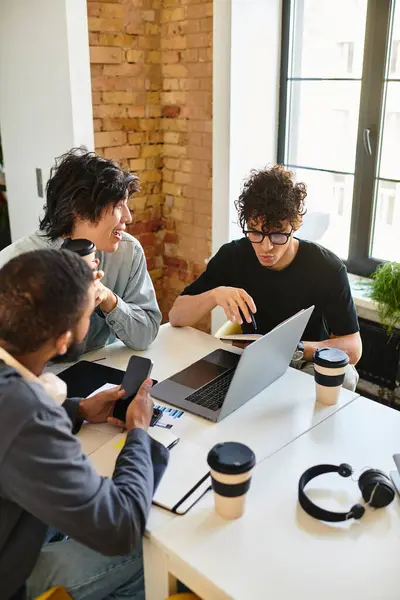 Three people discuss ideas and strategies over coffee in a lively work meeting. — Stock Photo