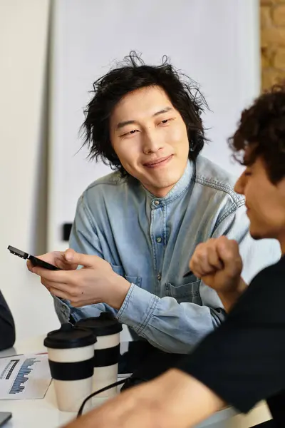 Zwei Mitarbeiter teilen Ideen und lachen an einem modernen Arbeitsplatz beim gemeinsamen Kaffee. — Stockfoto