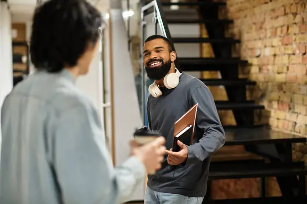 Two colleagues share a light moment while discussing work in an inspiring office environment. — Stock Photo