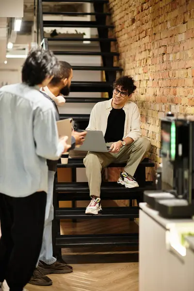 Os membros da equipe se envolvem em uma discussão dinâmica enquanto um indivíduo se concentra em seu laptop. — Fotografia de Stock