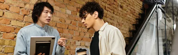 Two colleagues exchange innovative ideas while standing near a staircase in a trendy workspace. — Stock Photo
