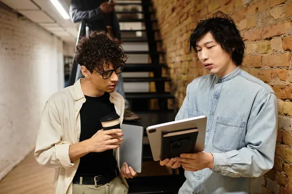 Two professionals discuss intently over a tablet in a modern workspace. — Stock Photo