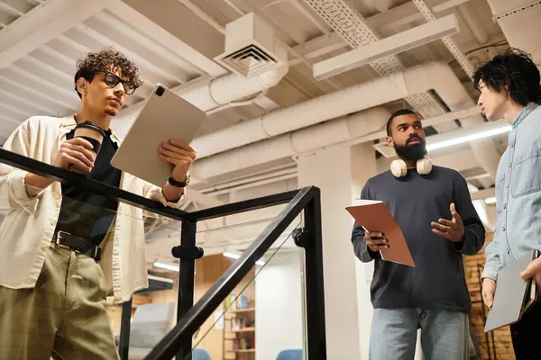 Team members discuss project ideas while reviewing digital and printed materials in the office. — Stock Photo