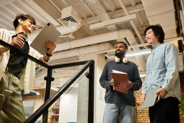 Three colleagues share ideas and insights while standing in a bright workspace filled with energy. — Stock Photo