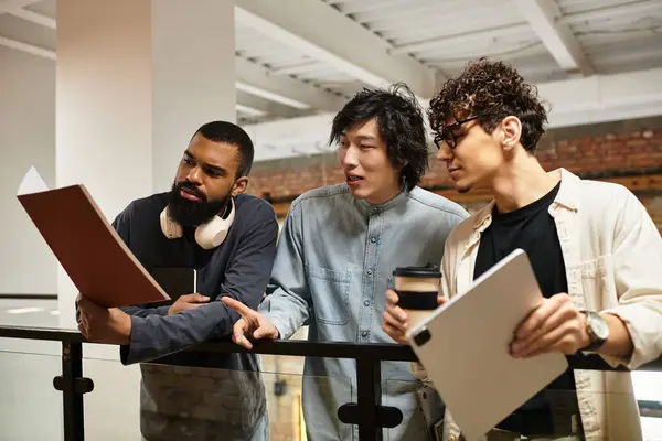 Three professionals engage in a collaborative discussion over documents in an open office space. — Stock Photo