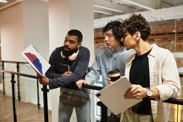 Three professionals discuss project plans while reviewing documents. — Stock Photo