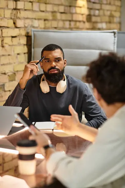 Two colleagues converse intently in a contemporary office, brainstorming ideas together at a desk. — Stock Photo
