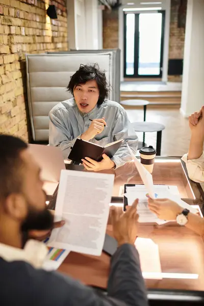 Colleagues gather around a wooden conference table, exchanging ideas and notes during work hours. — Stock Photo