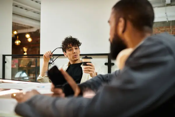 Two professionals chat over drinks in a modern workspace. — Stock Photo