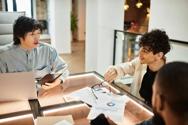 Dos profesionales discuten ideas sobre documentos y dispositivos en un ambiente de oficina elegante. - foto de stock