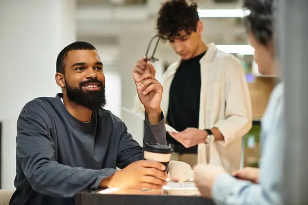 Two professionals engage enthusiastically over coffee in a lively office setting. — Stock Photo