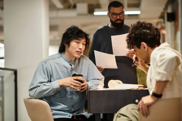 Tre persone discutono idee e recensiscono documenti a un tavolo in un ufficio moderno. — Foto stock