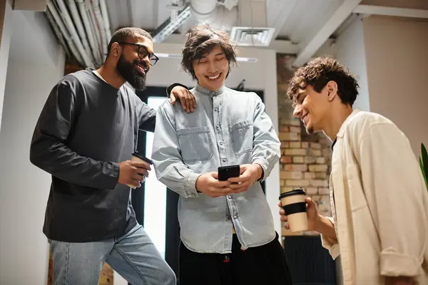 Three coworkers share a light moment, discussing ideas while enjoying coffee in a modern office. — Stock Photo