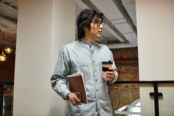 Un paio di occhiali uomo in abbigliamento casual gode di caffè con quaderni in uno spazio di lavoro vibrante. — Foto stock