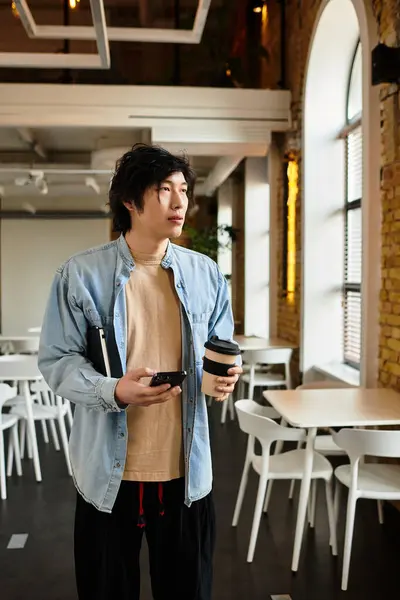Giovane in un ufficio luminoso in possesso di una tazza di caffè e perso nel pensiero. — Stock Photo
