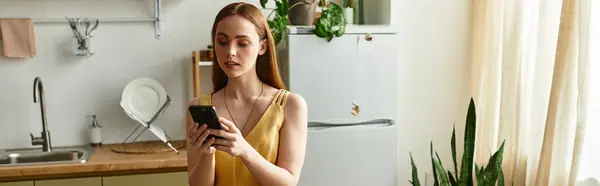 En una cocina soleada, una mujer joven se absorbe en su teléfono inteligente en medio de plantas exuberantes. — Stock Photo
