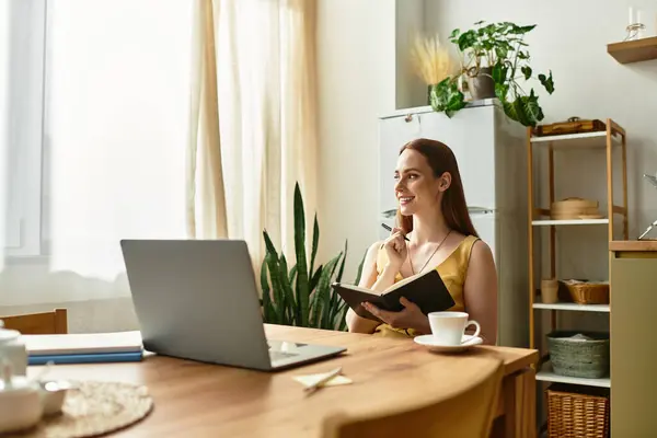 Beautiful woman smiles while noting ideas in her notebook at a bright wooden table. — Stock Photo