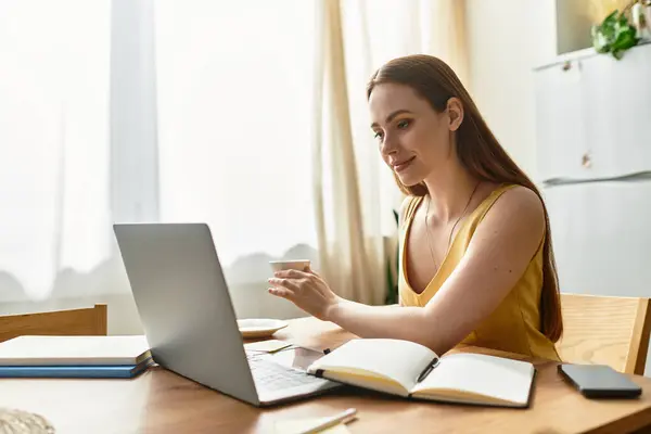 Young beautiful woman smiles while participating in an online meeting at her sunlit workspace. — Stock Photo