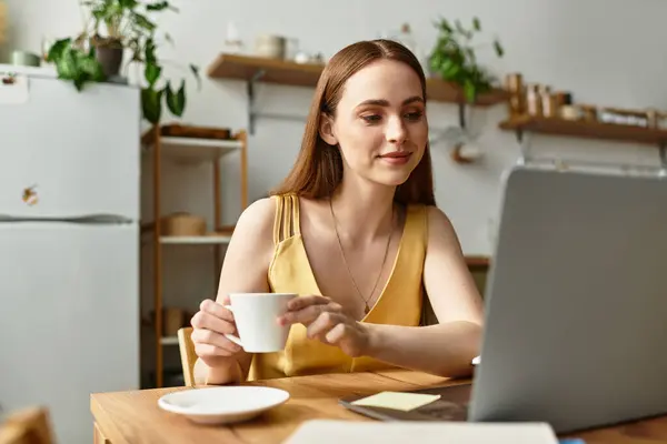 Bright and cheerful woman sips coffee, focused on her laptop amidst a stylish cafe atmosphere. — Stock Photo
