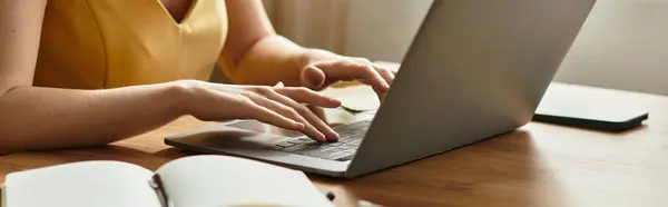 Una mujer joven escribe atentamente en su computadora portátil en un acogedor, invitando a casa. - foto de stock