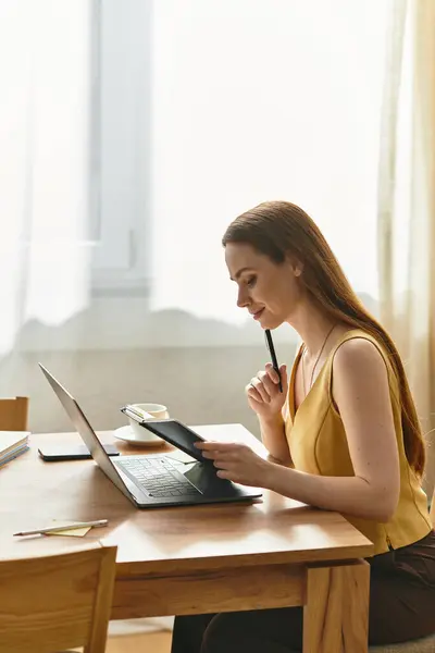 Young woman with long hair sits thoughtfully at her desk, writing while enjoying natural light. — Stock Photo