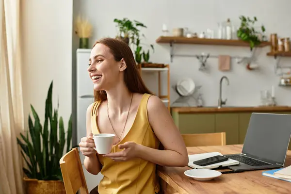 Bright and cheerful woman relaxes with coffee while surrounded by greenery in a stylish kitchen. — Stock Photo