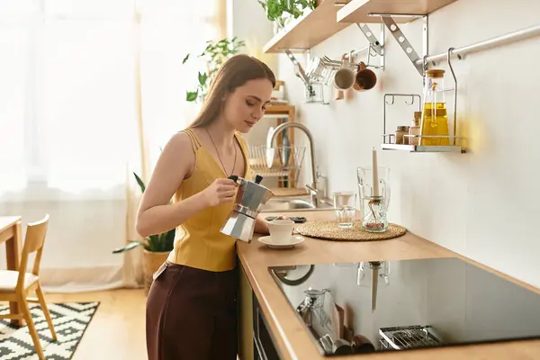 In a bright kitchen, a beautiful young woman brews coffee, savoring the serene morning atmosphere. — Stock Photo