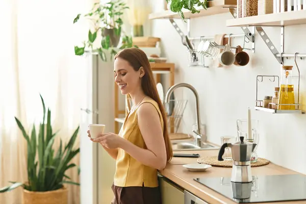 A young woman relaxes with coffee in a bright kitchen filled with greenery. — Stock Photo