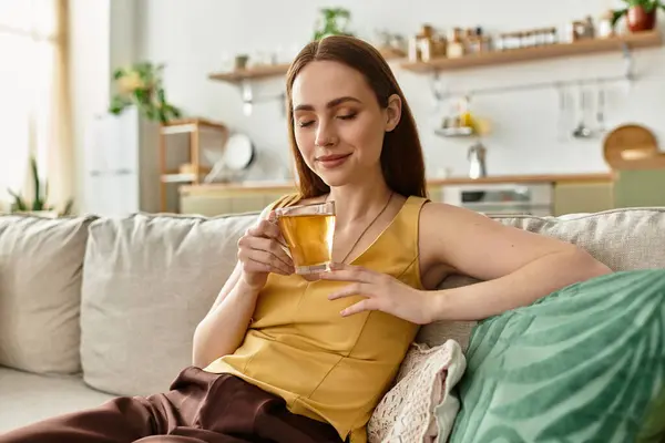 A young woman enjoys warm tea in her chic and cozy living room. — Stock Photo