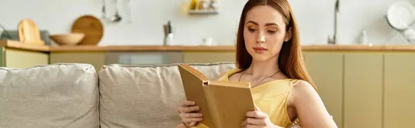 A young woman relaxes on a sofa, engrossed in a book in a stylish living room. — Stock Photo
