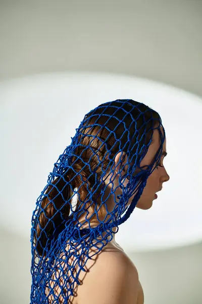 A young woman showcases elegance with blue netting in her hair against a soft background. — Stock Photo