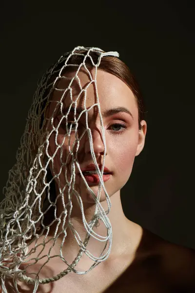 A young woman poses gracefully, her face partly veiled by delicate netting, adding intrigue. — Stock Photo