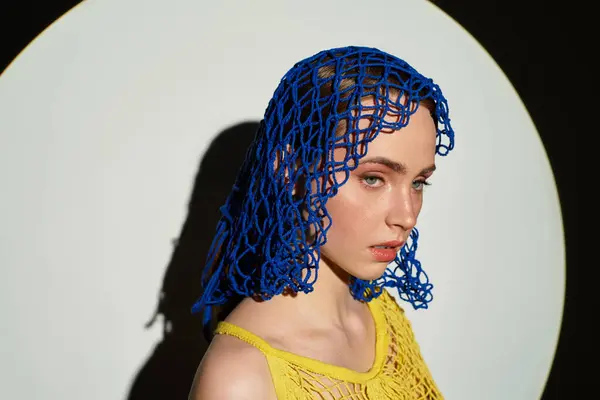 A beautiful woman in a unique blue headpiece exudes charm in a striking setting. — Stock Photo