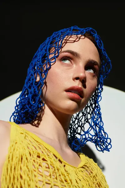 Young woman in a unique blue headpiece stands confidently, radiating style and poise. — Stock Photo