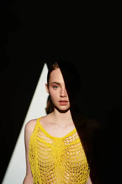 A confident young woman shows off her unique outfit under intriguing sunlight patterns. — Stock Photo