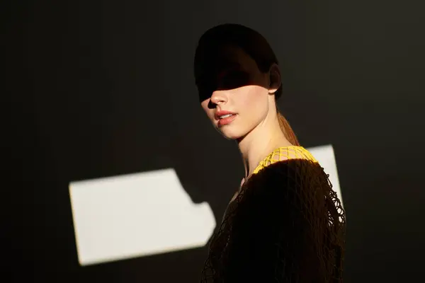 Junge schöne Frau steht anmutig, während Licht faszinierende Muster über ihr Gesicht schafft. — Stockfoto
