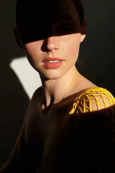 Young woman adorned in a unique outfit, captivated by dramatic lighting and shadows during midday. — Stock Photo
