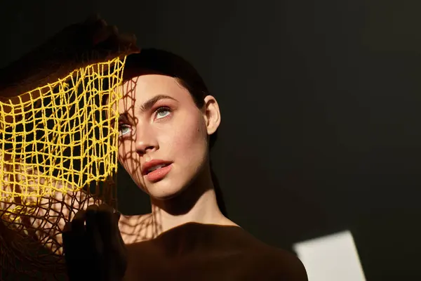 A young woman playfully interacts with a bright yellow net, accentuating her features. — Stock Photo