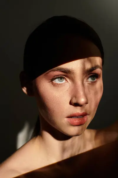 Une jeune femme regarde attentivement comme la lumière douce jette des ombres délicates sur son visage. — Stock Photo