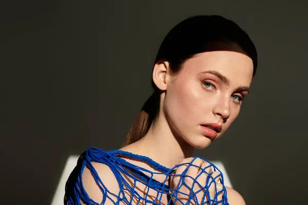 Une jeune femme frappante dans une tenue bleue est mise en évidence par un éclairage doux. — Photo de stock