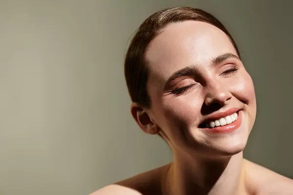 A young woman radiates happiness with a bright smile while enjoying soft light in a creative space. — Stock Photo