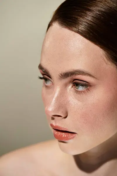 A young woman radiates grace with her flawless skin and striking eyes on a soft background. — Stock Photo