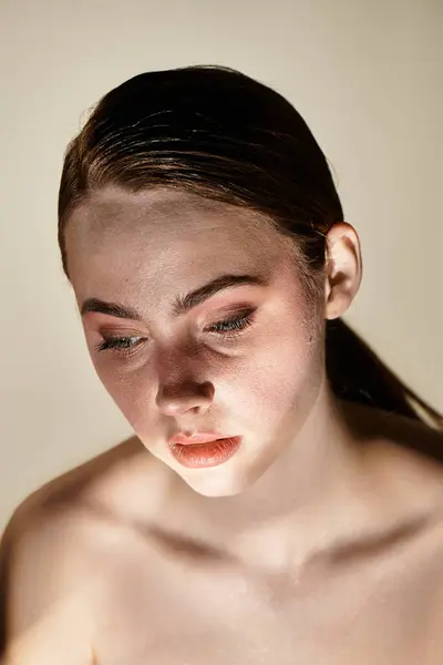 A young woman gazes downward, surrounded by soft, warm light that highlights her beauty. — Stock Photo