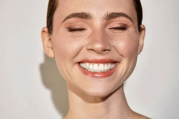 A young beautiful woman beams with happiness, showcasing her glowing skin and radiant smile. — Stock Photo