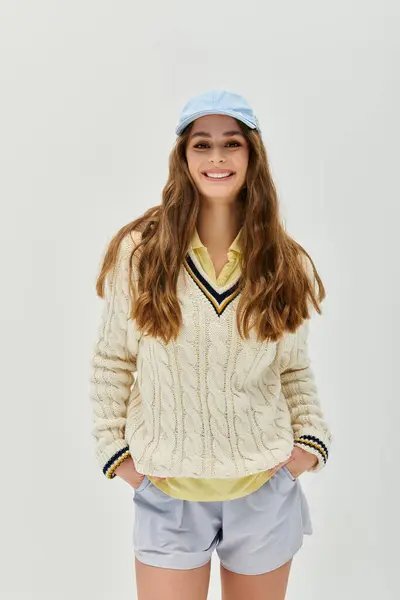 Una joven alegre muestra su estilo en un suéter acogedor y una gorra juguetona. - foto de stock