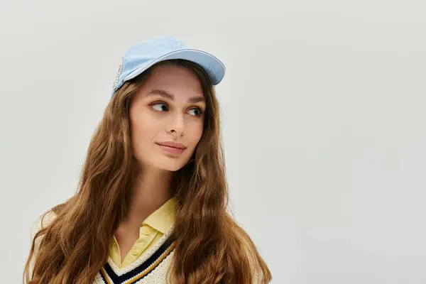 Una mujer joven en un suéter acogedor y gorra muestra su estilo en un momento relajado. - foto de stock