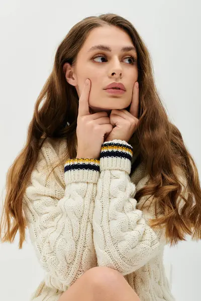 Bella giovane donna trasuda eleganza mentre premurosamente poggia il mento sulle mani al chiuso. — Foto stock