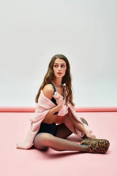 A young woman in a cozy setting flaunts her style wearing a soft pink layer. — Stock Photo