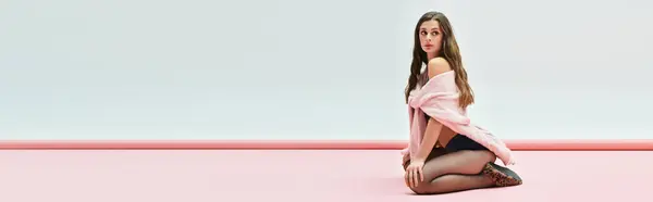 Молода жінка виявляє чарівність і впевненість, сидячи на м'якій рожевій поверхні. — Stock Photo